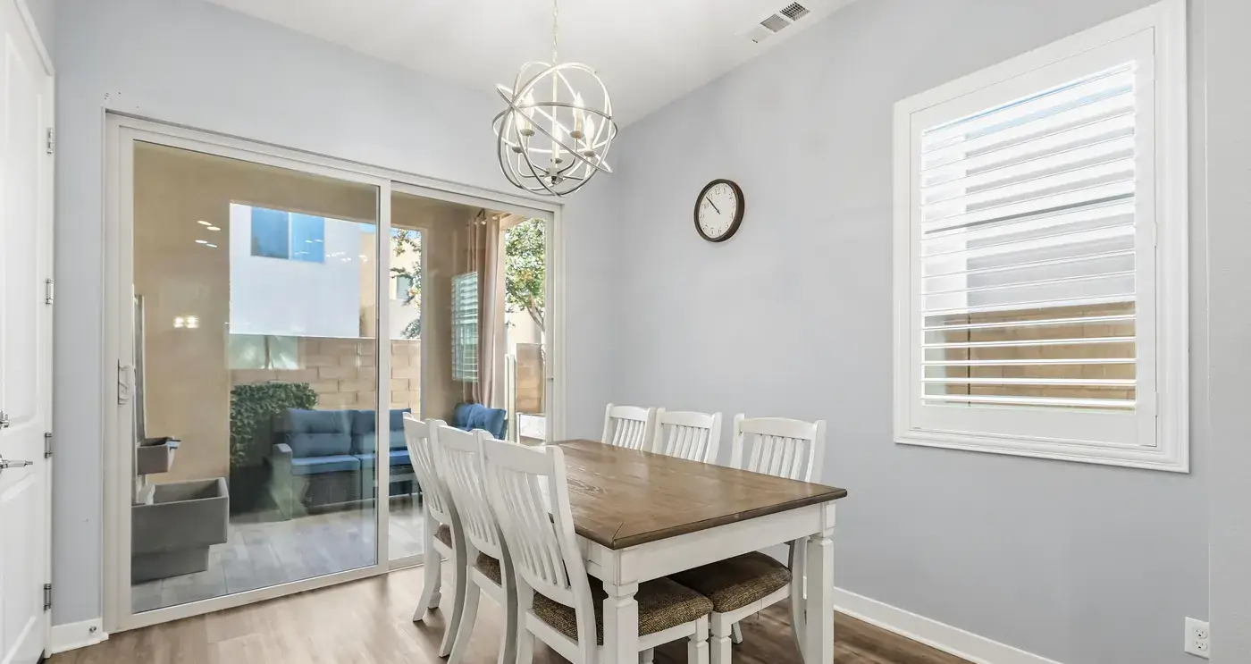 The dining area: a white table and chairs under an orb chandelier, the sliding door to the patio at the left