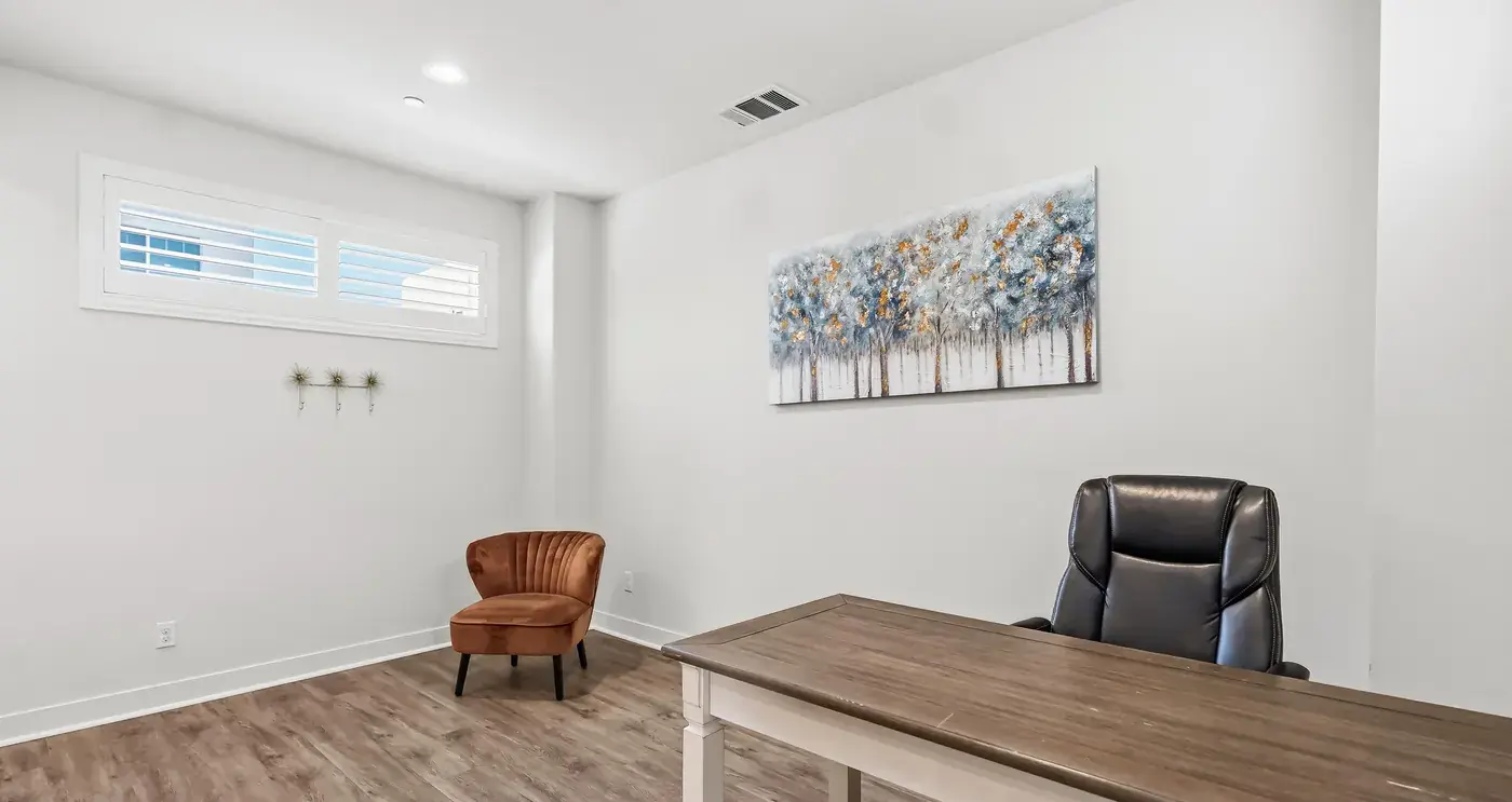 The loft: a desk, a leather chair and a painting of trees under a high window
